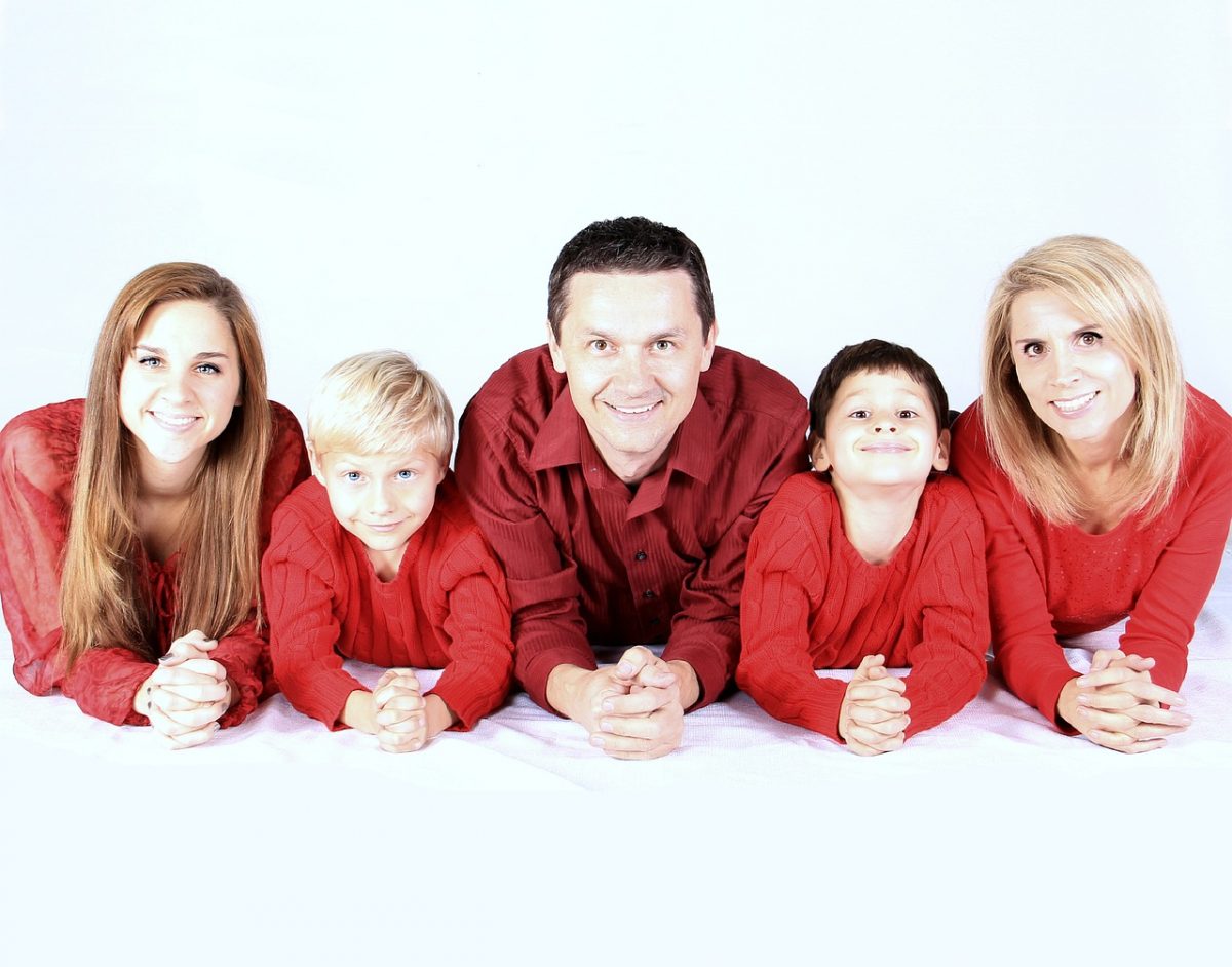 A family lay on their stomachs while smiling at the camera. Learn how a parenting counselor in Arcadia, AZ can offer support by searching for family counseling Phoenix or internal family systems therapy in Arcadia, AZ today.