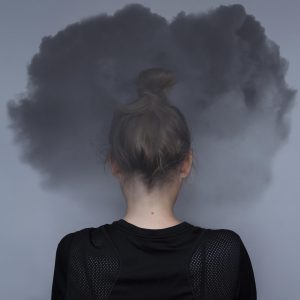 A woman stands with a dark could around her head. This could represent the stress an anxiety therapist in Arcadia, CA can address through anxiety treatment in Biltmore, AZ.