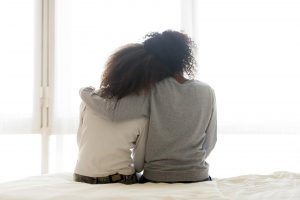 A mother and daughter sit together at the end of a bed while looking out the window. Learn how a therapist in child Arcadia, AZ can offer support for you and your child. Search "child counseling phoenix az" to learn more about therapy in Arcadia, AZ and more!