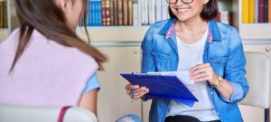 A child sits arcoss from a woman with a clipboard and a smile. This could represent the support depressoin treatment in Arcadia, AZ can offer. Learn more from a child therpaist in Phoenix, AZ or search " depression counseling phoenix" for support with overcoming child depression. 